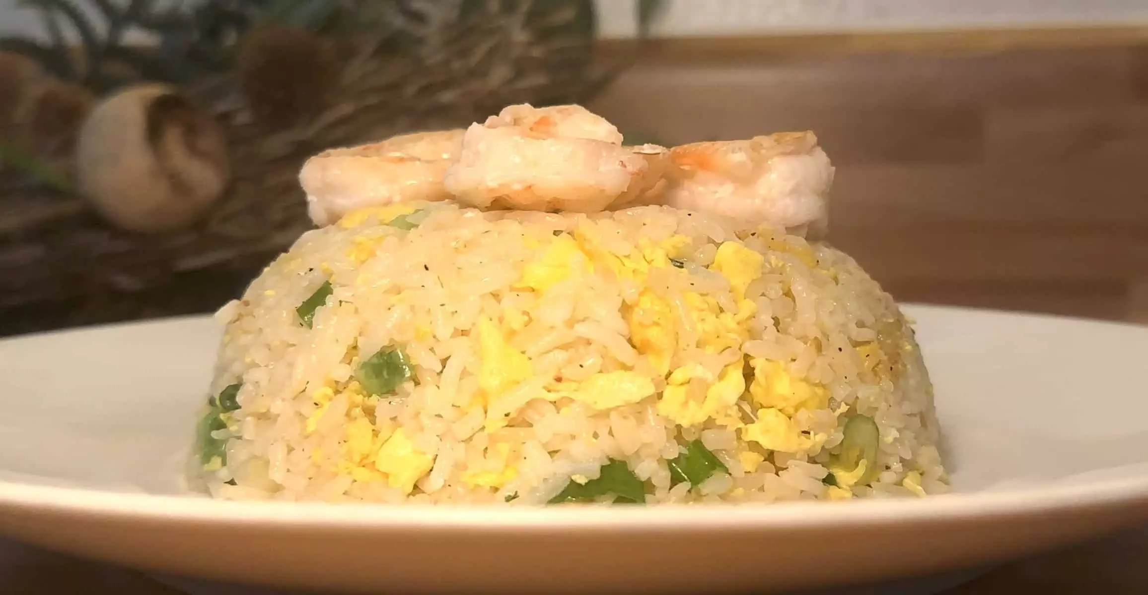 Shrimp fried rice with eggs and green onions served on a white plate in a close-up view.